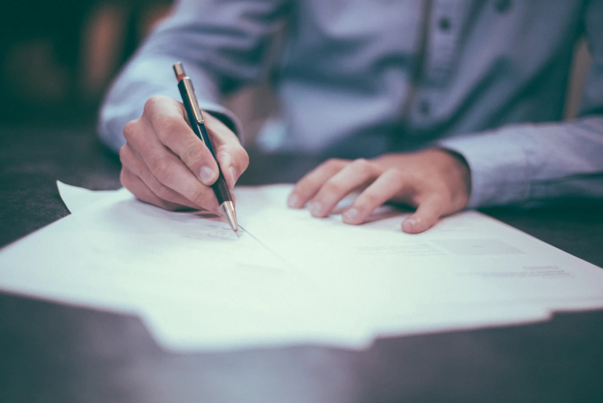 Accountant writing on the paper with pen.